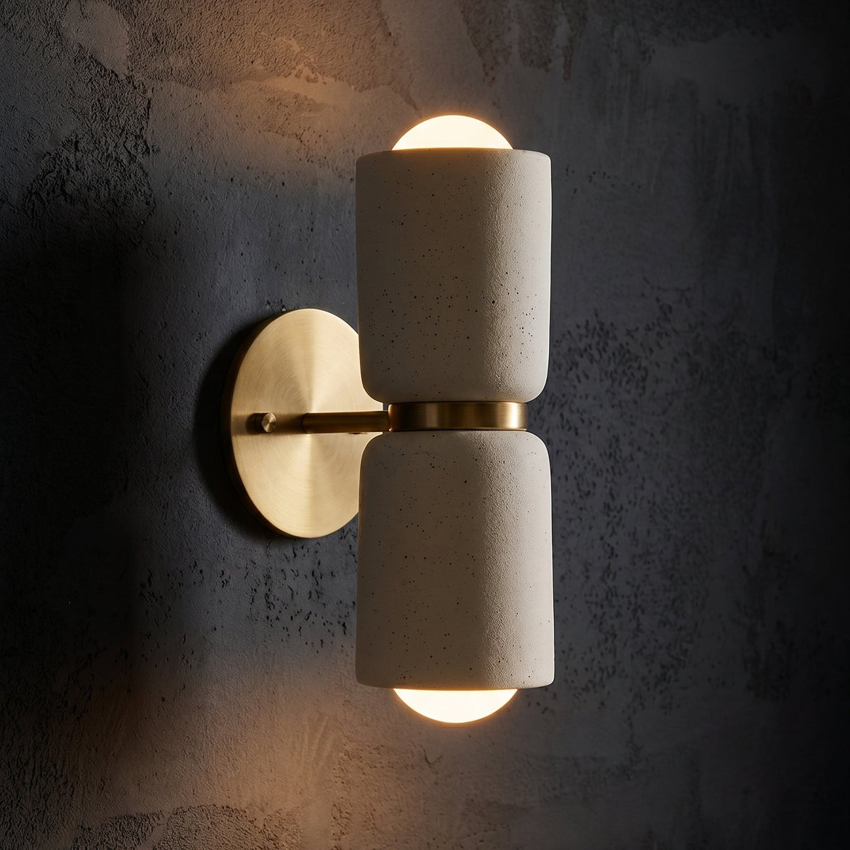 AX163 ceramic and brass wall sconce glowing on a dark textured wall, modern up down wall light