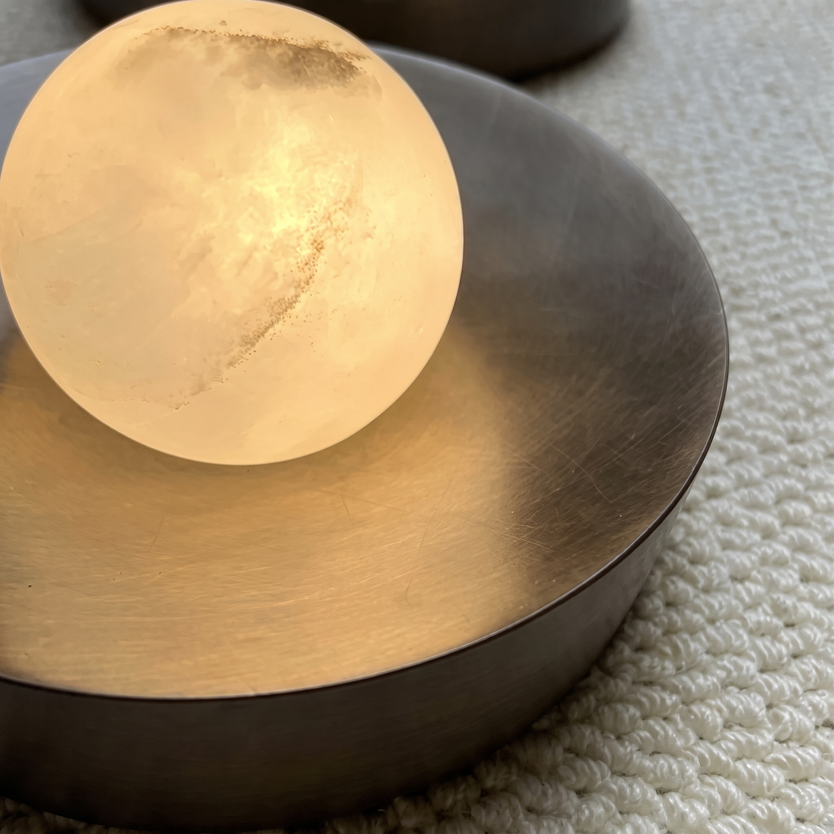 Close-up of illuminated alabaster sphere on bronze dish wall sconce